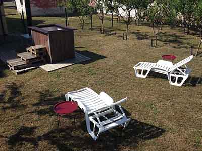 Outdoor wood-fired hot tub with sun loungers in a private garden in Subotica